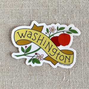 May include: A yellow banner with the word "Washington" on it, with a red apple and a branch of white flowers.