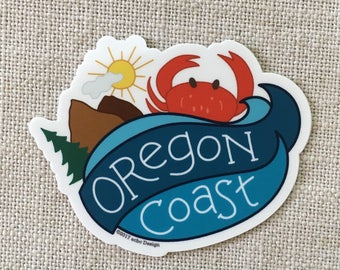 May include: A blue and white sticker with the text "Oregon Coast" in a white banner. A red crab with black eyes is on top of the banner. A brown mountain with a white cloud and a yellow sun are in the background.