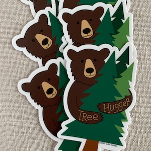 May include: A brown bear hugging a green pine tree with the text "Tree Hugger" on the sticker. The sticker has a white background and the text "&copy;2020 abc Design" at the bottom.