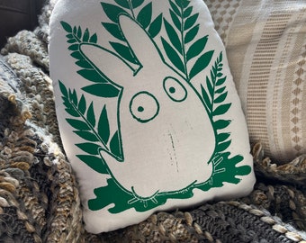 May include: White pillow with a green print of a cartoon bunny rabbit surrounded by ferns.
