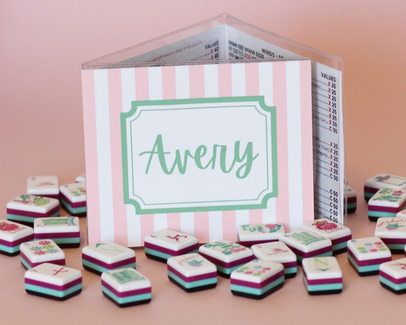 Puede incluir: Un tarjetero a rayas rosas y blancas con el nombre "Avery" en escritura verde. Peque&ntilde;as baldosas cuadradas decorativas con dise&ntilde;os florales y geom&eacute;tricos est&aacute;n dispersas frente al tarjetero.