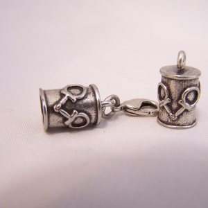 May include: Two silver-toned cylindrical cord ends with an antique finish, each featuring a raised equestrian bit motif. One cord end is attached to a lobster claw clasp, while the other features a small jump ring at the top for secure attachment.