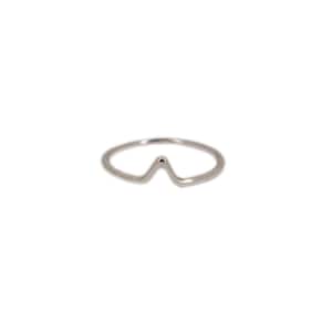 Pode incluir: Um anel prateado com um design minimalista. O anel apresenta uma forma simples, angular, de montanha ou onda no centro. A banda é fina e lisa, e o anel está sobre um fundo branco.