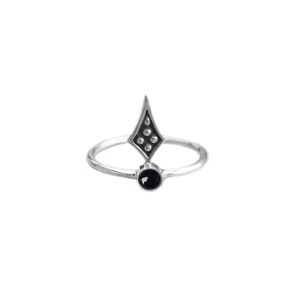 Peut inclure: Bague en argent avec une pierre noire et un motif en forme de losange. Le losange a un sommet pointu et quatre petits accents circulaires. La bague est posée sur un fond blanc.