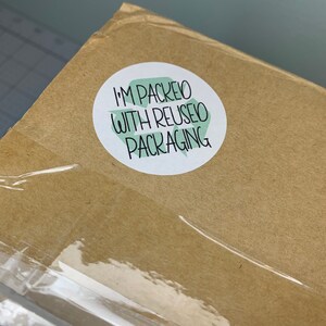 May include: A brown cardboard box with a white sticker that says "I'm packed with reused packaging".