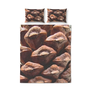 Könnte beinhalten: Bettwäsche-Set mit einem Nahaufnahme-Design einer Kiefernzapfen. Das Set beinhaltet einen Bettbezug und zwei Kissenbezüge, alle mit einem detaillierten, naturalistischen Muster. Die Farbpalette wird von Braun- und Beigetönen dominiert.