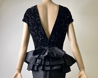 May include: A black velvet dress with a constellation print and a layered ruffle skirt. The dress has a deep V-neckline in the back.