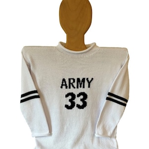 May include: White knitted sweater with black stripes on the sleeves and "ARMY 33" printed on the front.