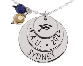 May include: Silver necklace with a layered pendant featuring the text "W.A.U. 2022 SYDNEY" and a graduation cap symbol. The necklace also has a blue and gold bead charm.
