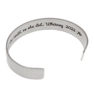 May include: Silver bangle bracelet inscribed with "She could, so she did... Whitney 2022"