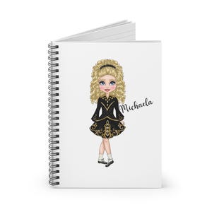 Può includere: Un quaderno a spirale con una copertina bianca che presenta un'illustrazione di cartone animato di una ragazza con un vestito da ballo irlandese nero e dorato. La ragazza ha i capelli biondi e gli occhi azzurri. Il testo "Michaela" è stampato sulla copertina.