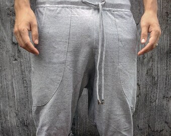 May include: Gray sweatpants with a drawstring waist and cuffed legs. The sweatpants are paired with white low-top sneakers.