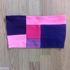May include: A pink and purple patchwork tube top with a navy blue trim.