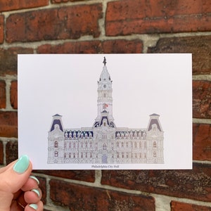 May include: A black and white line drawing of Philadelphia City Hall, a historic building with a tall tower and a clock face. The drawing is on a white background.