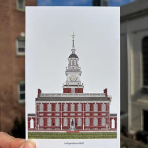 May include: A postcard featuring a detailed illustration of Independence Hall in Philadelphia. The building is rendered in red brick with white accents, a clock tower, and a statue in front. The text "Independence Hall" is printed at the bottom.