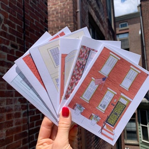 May include: A set of six illustrated cards featuring different brick houses with various architectural details. The cards are printed on white paper and have a slightly textured surface.