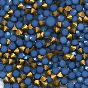 Pode incluir: Uma imagem de close-up de uma grande quantidade de strass azuis e dourados. Os strass estão espalhados aleatoriamente e parecem ser de vários tamanhos.