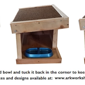 May include: A wooden pet food station with a slanted roof and a blue food bowl. The station is designed to keep pet food dry and fresh.
