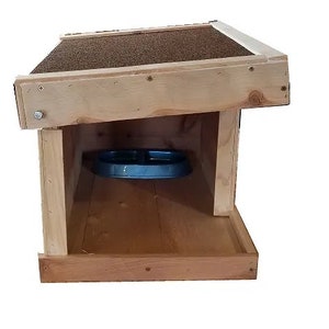 May include: A wooden dog house with a slanted roof and a blue food bowl inside. The house is made of natural wood and has a simple design.