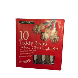 May include: A red box of Holiday Time Teddy Bears Indoor Glass Light Set. The box features the text "10 Teddy Bears Indoor Glass Light Set". The set has a lighted length of 7.8 feet (2.38 m). The total length is 9.5 feet (2.9 m).