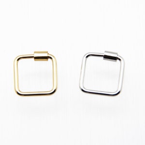 May include: Two square-shaped key rings, one gold and one silver, with a cylindrical bar at the top.