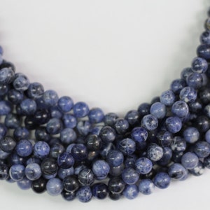 May include: A strand of blue and white gemstone beads. The beads are round and have a smooth, polished finish.