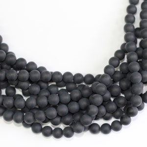 May include: A strand of black matte round beads. The beads are uniform in size and have a smooth, polished finish.