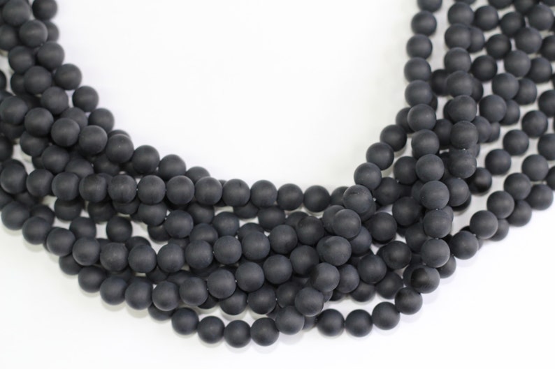 May include: A strand of black matte round beads. The beads are uniform in size and have a smooth, polished finish.