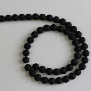 May include: A strand of black matte round beads. The beads are strung on a clear elastic cord.