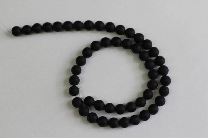 May include: A strand of black matte round beads. The beads are strung on a clear elastic cord.