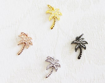 May include: Four palm tree charms with clear crystal accents. The charms are in gold, rose gold, silver, and black.