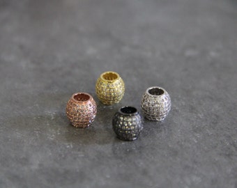 May include: Four round beads with a pave setting of clear rhinestones. The beads are in different metal finishes: rose gold, gold, silver, and black.