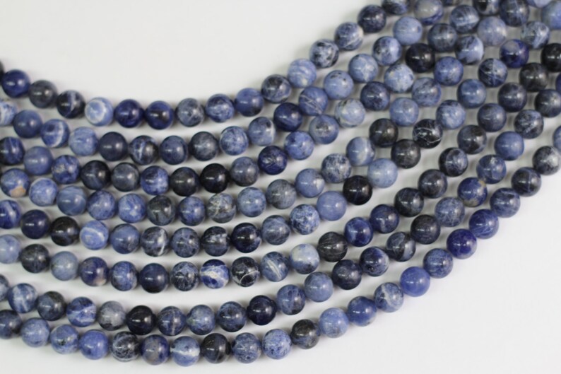 May include: A strand of blue and white gemstone beads. The beads are round and have a smooth, polished finish.