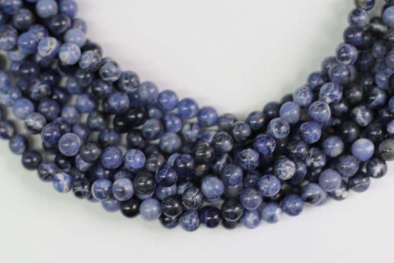 May include: A strand of blue and white gemstone beads. The beads are round and have a smooth, polished finish.