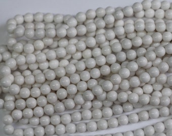 May include: A strand of white round beads, made of natural stone, for jewelry making.