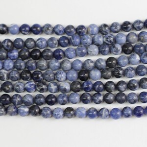 May include: A strand of blue and white gemstone beads. The beads are round and have a smooth, polished finish.