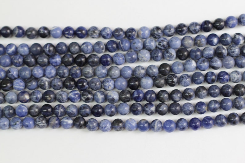 May include: A strand of blue and white gemstone beads. The beads are round and have a smooth, polished finish.