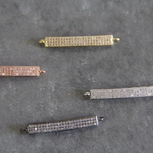 May include: Four bar-shaped connectors with a pave setting of clear cubic zirconia stones. The connectors are in gold, rose gold, silver, and black finishes.