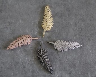 May include: Four feather charms with crystal embellishments in gold, silver, rose gold, and black finishes.