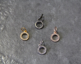 May include: Four small, round pendants with a circle of clear rhinestones around the edge. The pendants are in gold, silver, black, and rose gold.