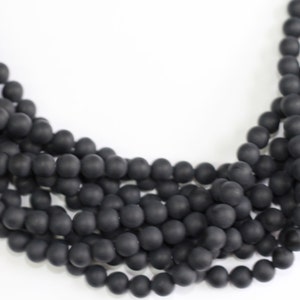 May include: A strand of black matte round beads. The beads are strung together on a clear thread.