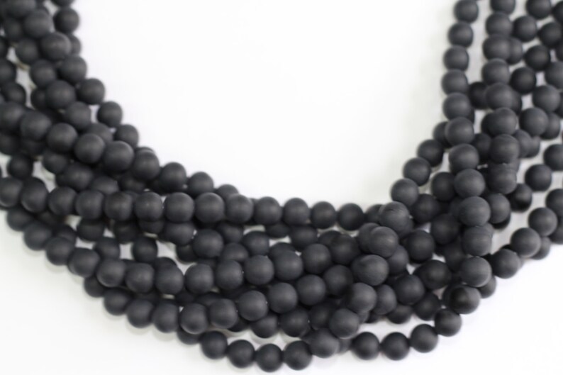 May include: A strand of black matte round beads. The beads are strung together on a clear thread.