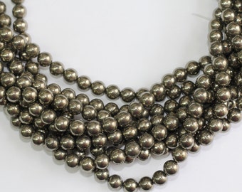 May include: A strand of round, metallic pyrite beads. The beads are a dark, silvery gray color and have a slightly iridescent sheen.