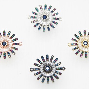 May include: Four silver evil eye charms with a blue center and a white and multi-colored crystal design. The charms have a loop on each side for attaching to jewelry.