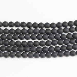 May include: A strand of black matte round beads. The beads are uniform in size and shape, and they are strung together on a clear thread.