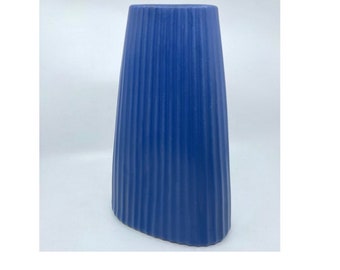 May include: A blue ceramic vase with a ribbed design. The vase is oval shaped and has a smooth, matte finish.