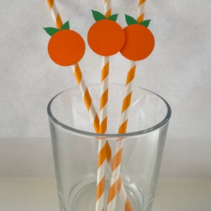 Peut inclure: Trois pailles en papier ray&eacute;es orange et blanc avec des d&eacute;coupes de fruits orange en haut. Les pailles sont dans un verre transparent.