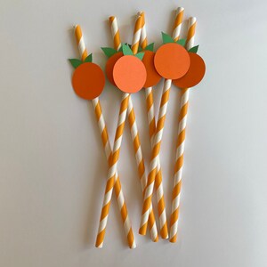 Peut inclure: Ensemble de six pailles en papier ray&eacute;es orange et blanches avec des d&eacute;coupes circulaires orange orn&eacute;es de feuilles vertes. Les cercles ont un contour blanc et sont attach&eacute;s aux pailles.