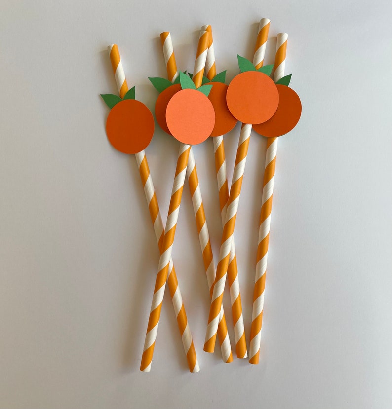 Peut inclure: Ensemble de six pailles en papier ray&eacute;es orange et blanches avec des d&eacute;coupes circulaires orange orn&eacute;es de feuilles vertes. Les cercles ont un contour blanc et sont attach&eacute;s aux pailles.