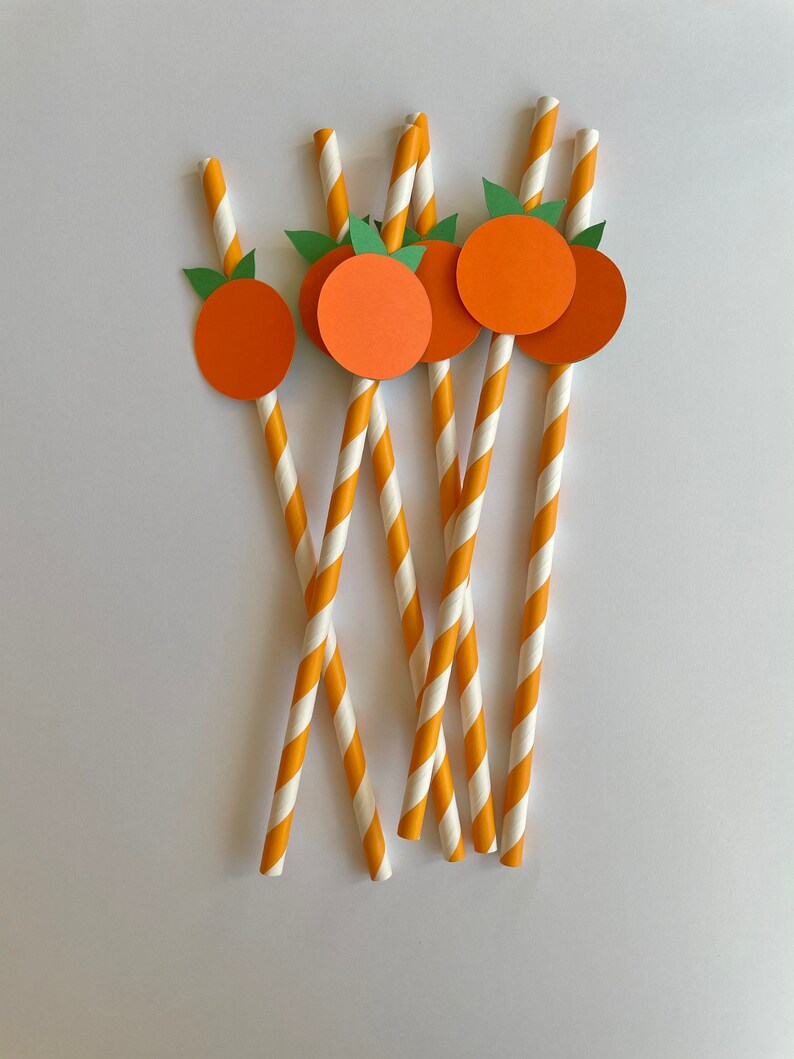 Peut inclure: Six pailles en papier ray&eacute;es orange et blanc avec des cercles en papier orange et des feuilles en papier vert attach&eacute;es au sommet de chaque paille.